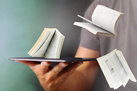 Picture of books flying out of tablet held by person